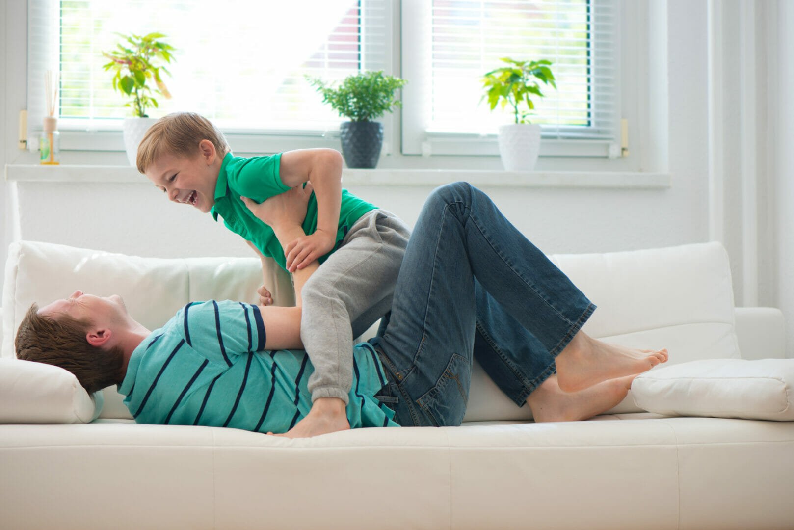 Little boy having fun with father on sofa at home